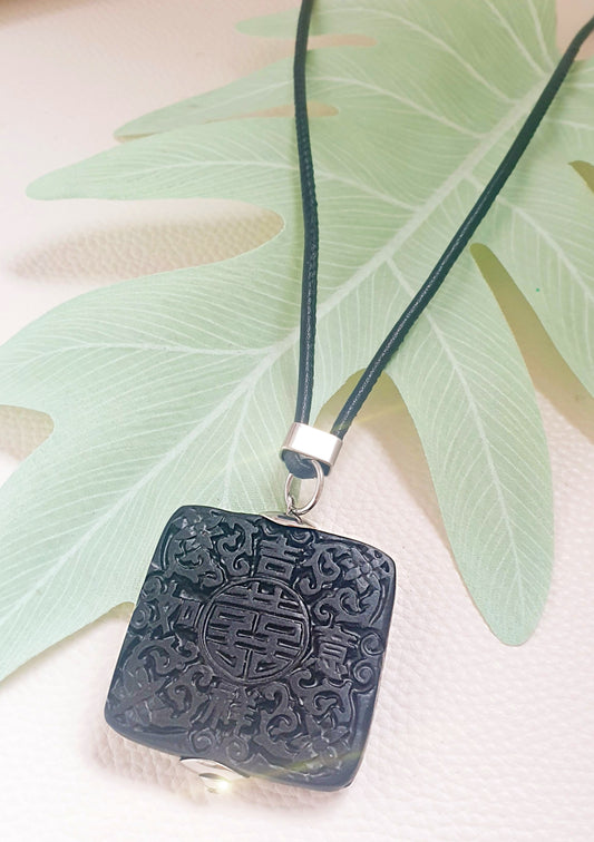 Großer, viereckiger Anhänger aus geschwärztem Horn mit chinesischen Glückssymbolen an Lederkette